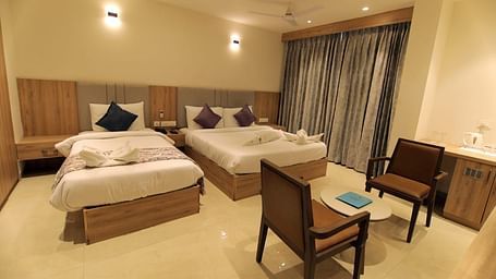 Well lit room at Hotel Mumbai House Express, Udaipur with twin beds and seating arrangement
