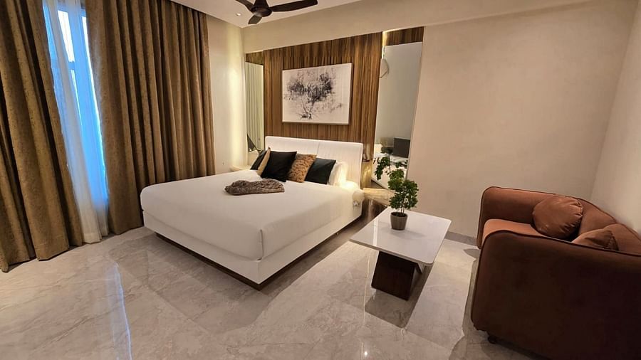 A cosy bedroom with a potted plant placed on a small table between the bed and the sofa at Hotel Mumbai House, Vashi.