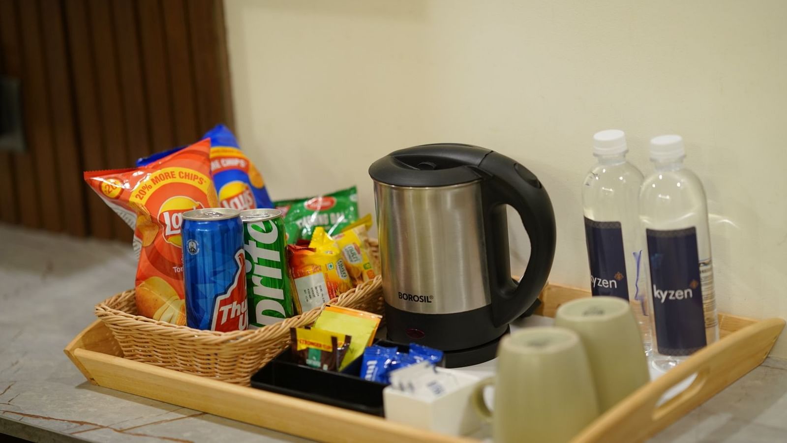 A hospitality tray with snacks, a kettle, and water bottles arranged neatly for guests at Hotel Kyzen Smartstays – Smart, Reliable, Kyzen