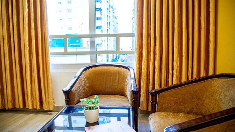 Two sofa chairs and a coffee table in a room with a glass window Sun Park Hotel & Banquet, Chandigarh - Zirakpur
