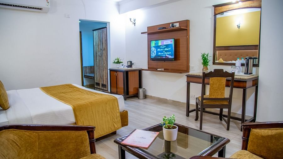 A side view of a room with a bed, TV, writing desk, coffee table and chairs | Sun Park Hotel & Banquet, Chandigarh - Zirakpur