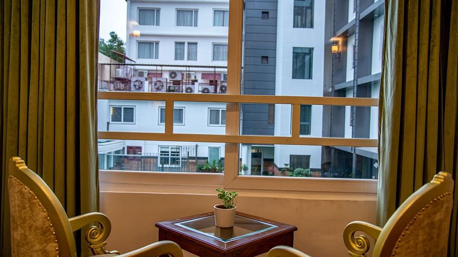 Two sofa chairs facing each other beside a window that has a pool view | Sun Park Hotel & Banquet, Chandigarh - Zirakpur  