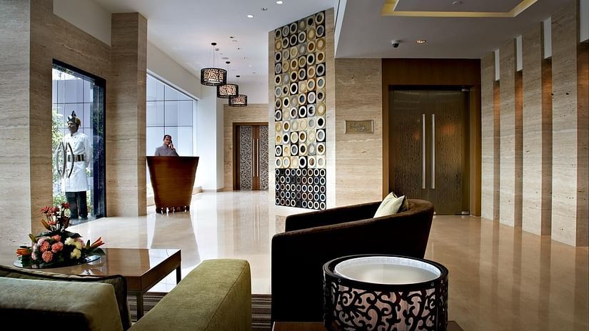 A modern hotel lobby with comfortable seating, a reception desk, and stylish architectural details - Adarsh Hamilton.