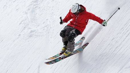 A close up shot of a person wearing a red jacket skiing on the slopes.