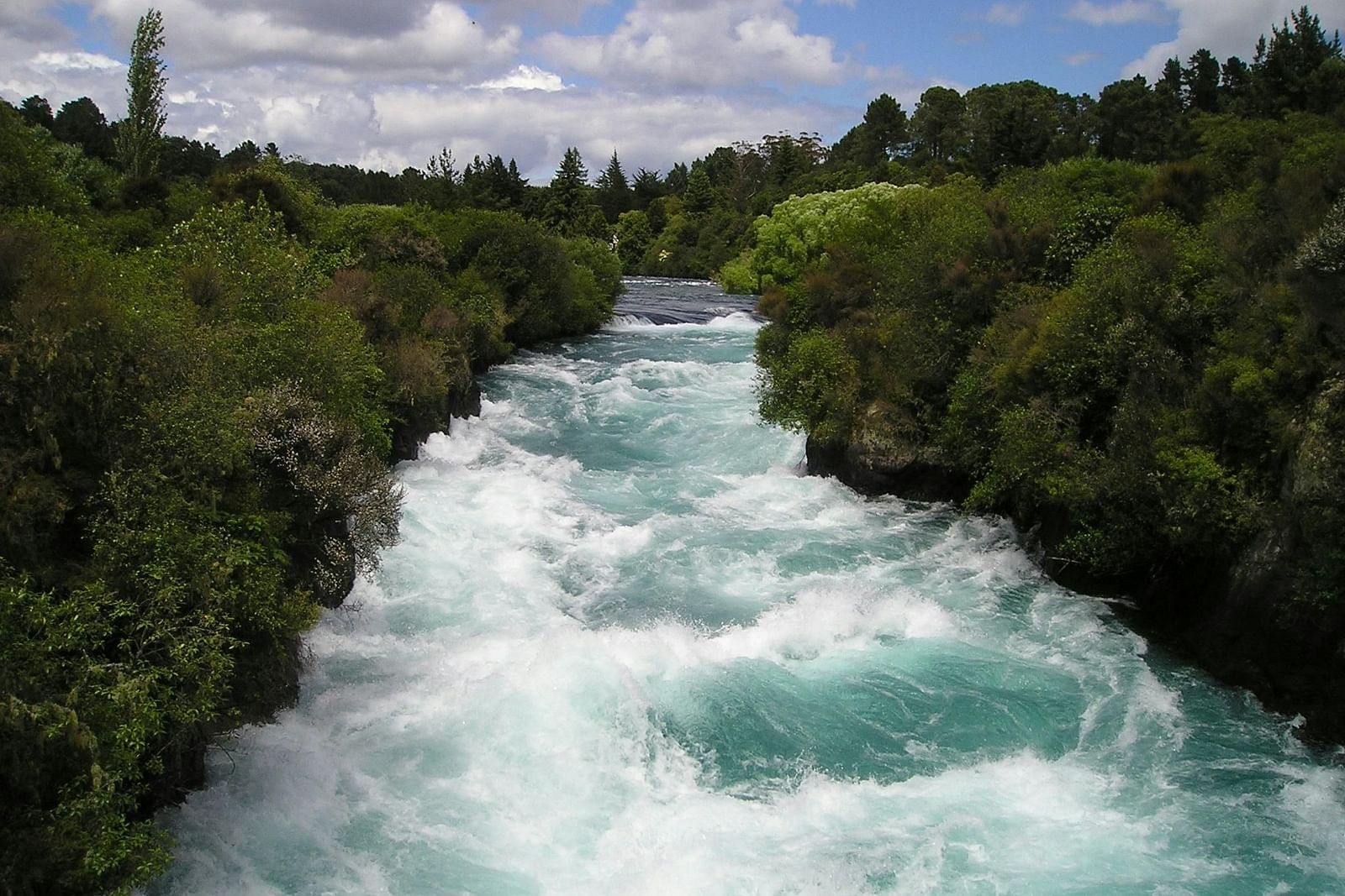 image of a river with strong currents flowing with lush greenery on either sides of the river bank