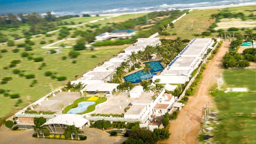 An aerial view of a resort complex with multiple white buildings and swimming pools along a coastline | Grand Bay Resort and Spa