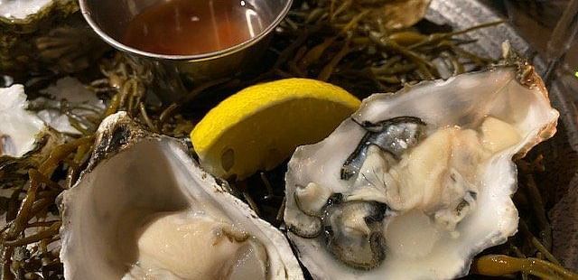 Fresh oysters on the half shell served with a mignonette sauce and lemon wedges.