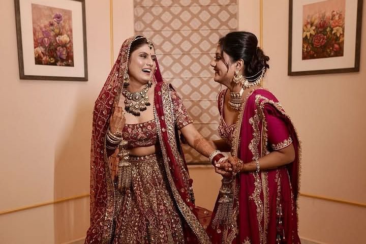 The bride and her bridesmaid share a joyful moment, dressed in lehengas, adorned with intricate embroidery. - Umaid Palace - A Lakeside Heritage Palace Resort