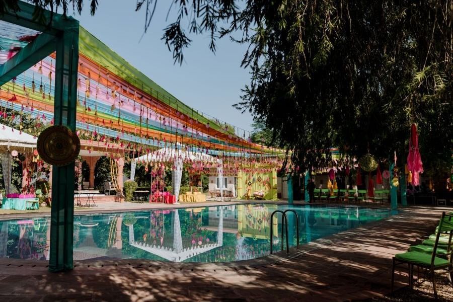 A poolside wedding venue with green foliage covering the shot- Umaid Palace - A Lakeside Heritage Palace Resort