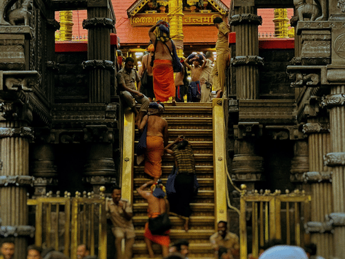 People gathered inside a temple corridor with carved pillars and a decorated shrine visible in the background.