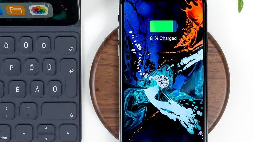 Phone getting wirelessly charging next to a tablet and a potted plant above it