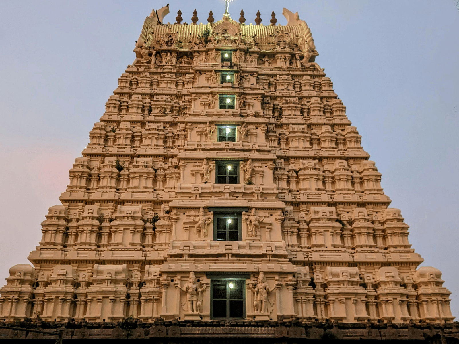 A close up facade shot of a temple featuring the entrance along with a beautiful evening sky in the background.