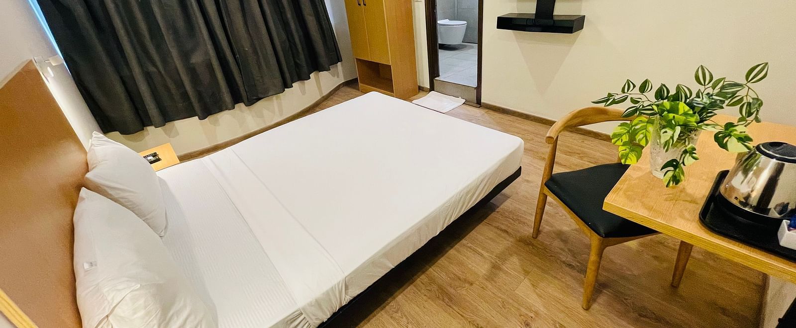 A room at Sanctum Suites Richmond Road, Bangalore with a double bed, a television, and a tea coffee maker placed on a table.