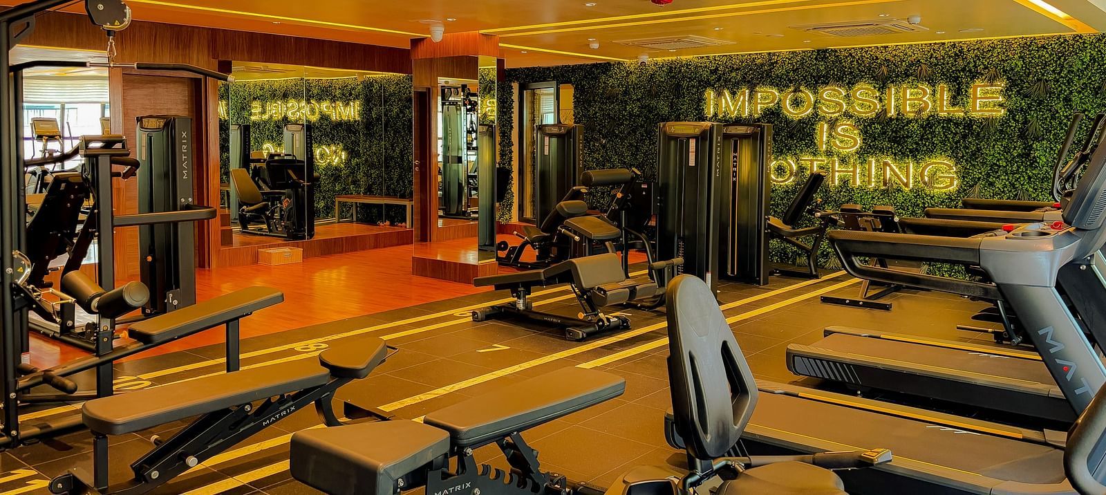 Fitness Center at KertelSuites, featuring modern gym equipment and the motivational quote Impossible is Nothing displayed
