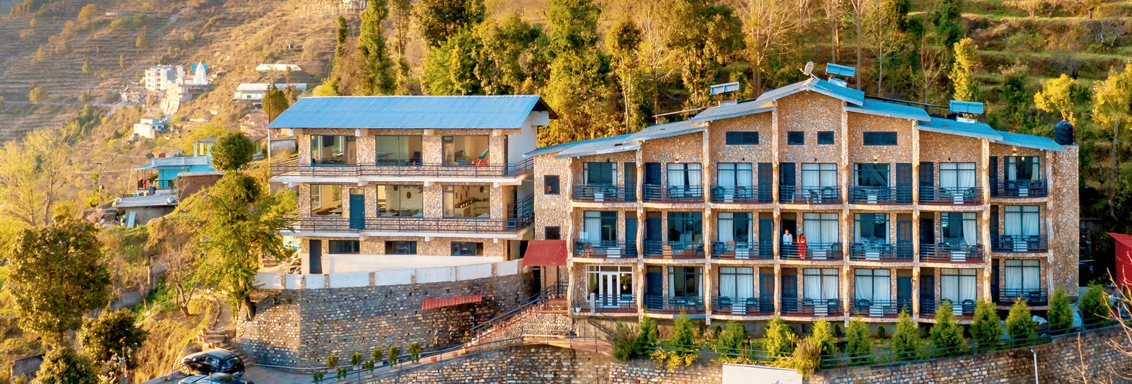 A high-angle exterior view of the Himalayas Resort By The Lake Hill, Mukteshwar building built into the side of the hill.
