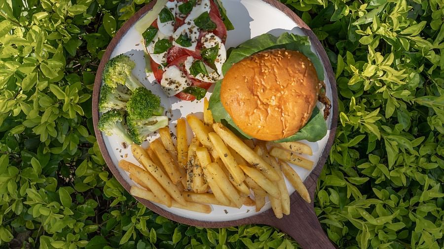 a platter of burger, french fries, caprese salad and vegetables - Neer Ganga Resorts
