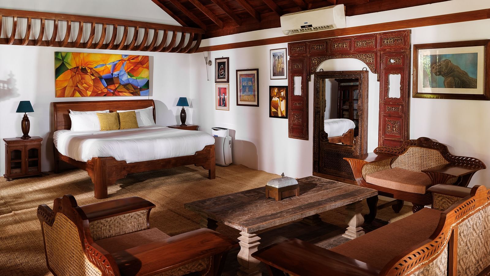 A wooden interior room with wooden furnitures such as a bed, a sofa set, a coffee table, and paintings - BluSalzz Villas - Muhamma Resort, Alleppey