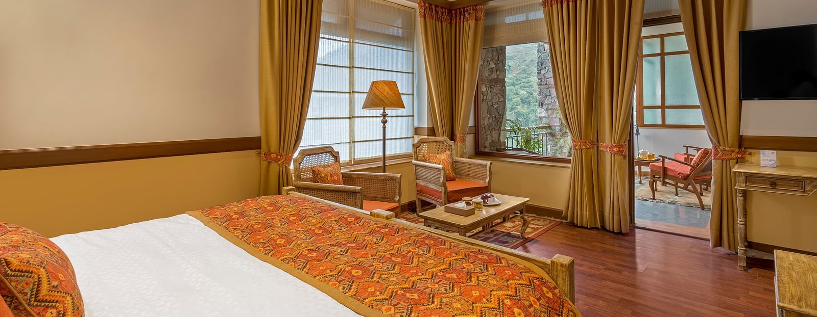 Top-side angle view of Superior Rooms at Fishermen's Lodge, Bhimtal, showcasing a plush bed, lamp stand, and flat-screen TV for a luxurious stay.