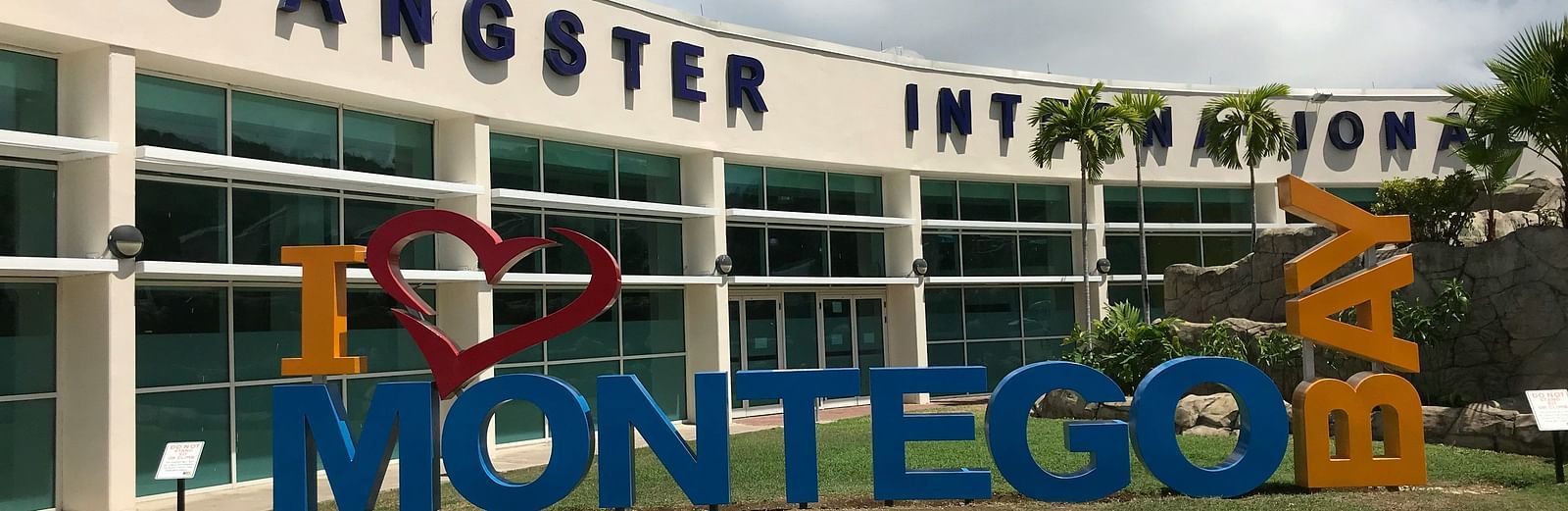 A signage of Montego Bay in front of the local airport with a walking path in front of the signage.