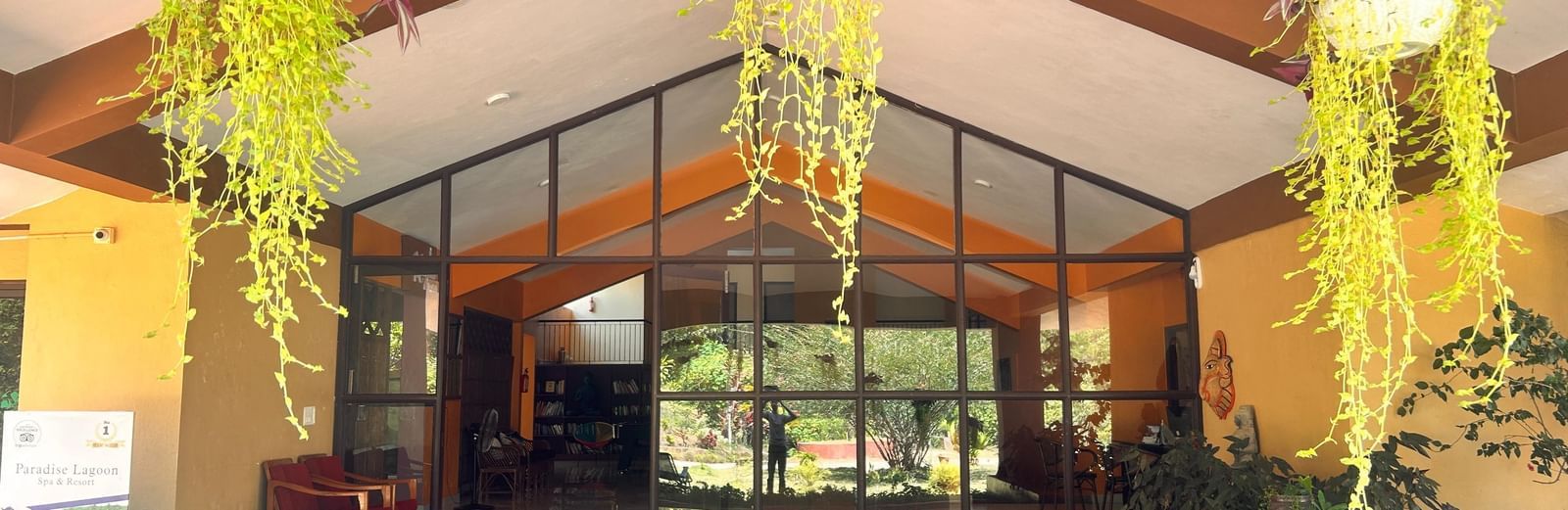 The beautiful main entrance to Paradise Wild Hills Resort, Kollur, with hanging plants and large glass doors.
