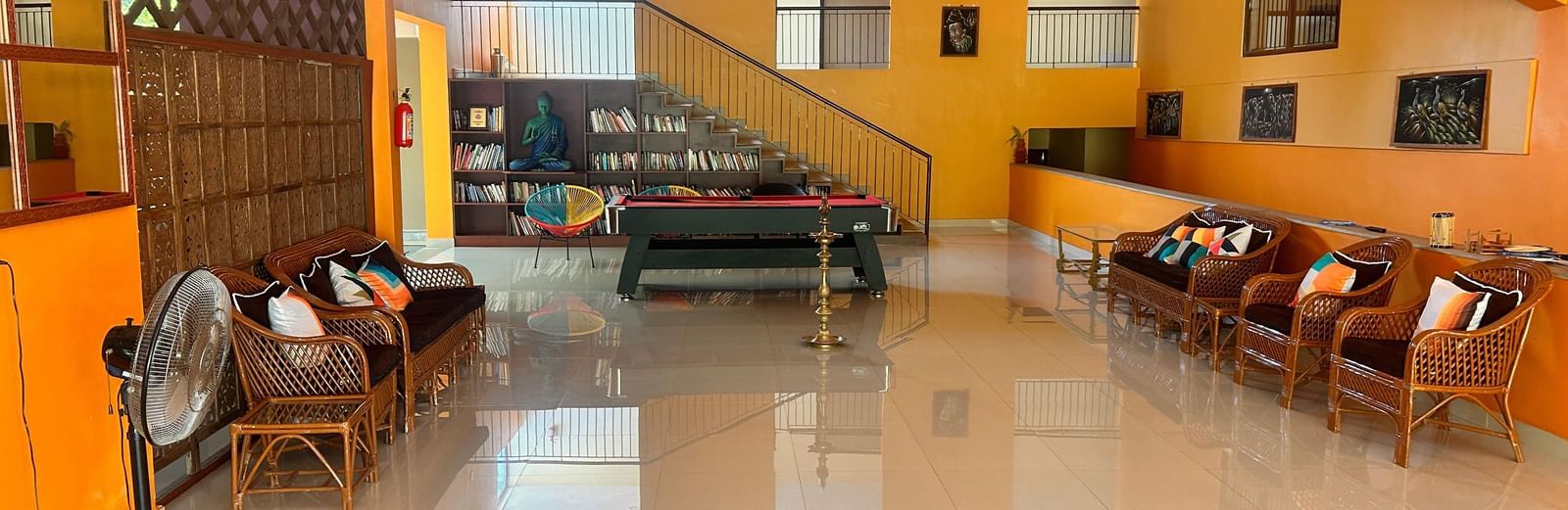 The recreation area at Paradise Wild Hills Resort, Kollur, with a pool table, staircase, and comfortable rattan furniture.