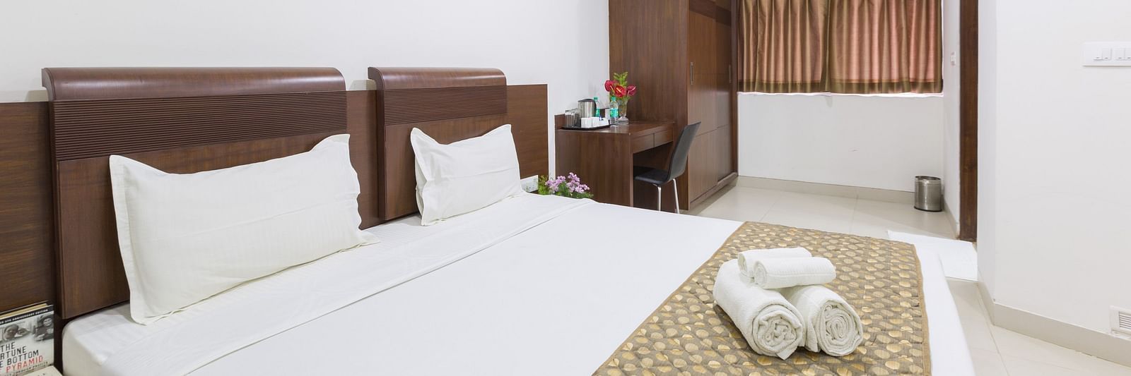 A room with a double bed, a patterned bed runner, a work and a chair, and a wardrobe - Sanctum Suites BEL Road, Bangalore
