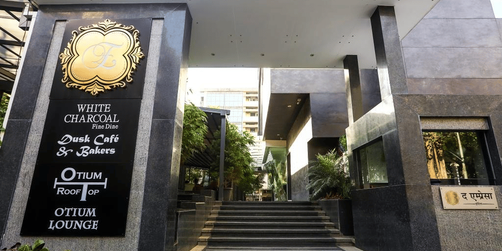 Grand building entrance featuring dark granite columns, steps leading up, and black signage plaques on the side.