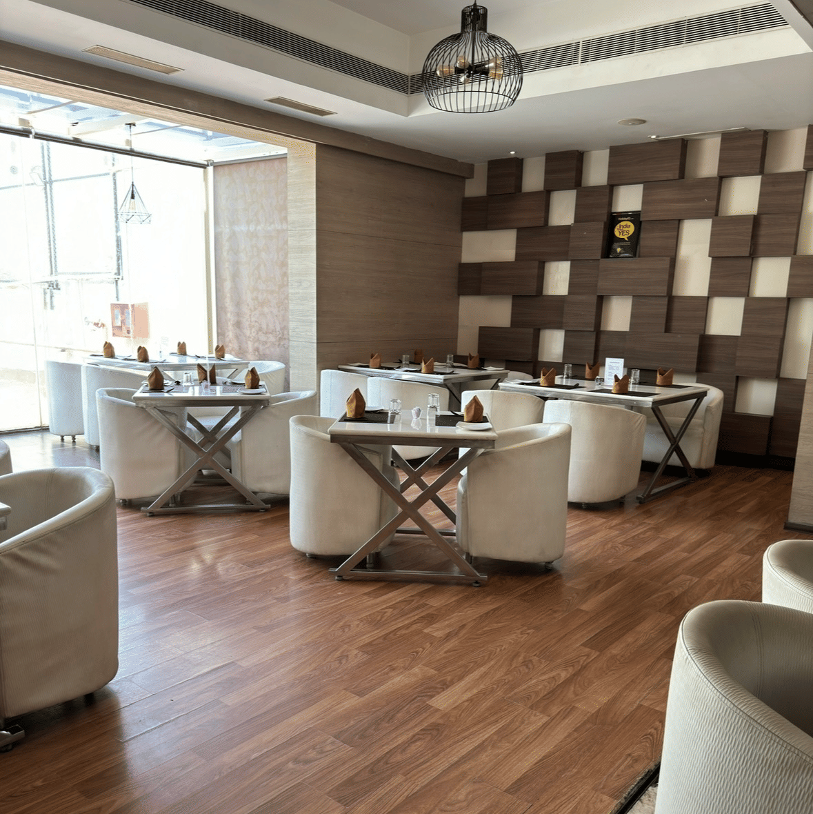An elegant dining area at Cenneys Gateway with wooden flooring, neatly arranged chairs and tables and contemporary decor.