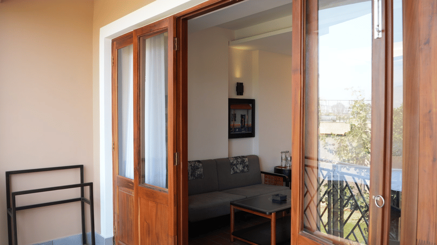 A balcony view featuring a clothes drying rack and open wooden glass doors leading into a room with a sofa at Hotel Sonar Bangla, Ajodhya Hills.