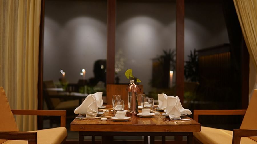 Seating arrangement at Asian Table at Saraca Resort & Spa Corbett with a wooden theme and large windows at night
