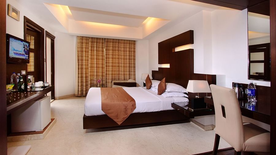A well-appointed hotel room with a plush bed, contemporary furnishings, and a warm, inviting ambience at The President Hotel, Jayanagar