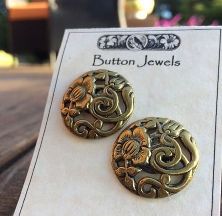 A pair of intricately designed earrings displayed on a branded jewelry card.