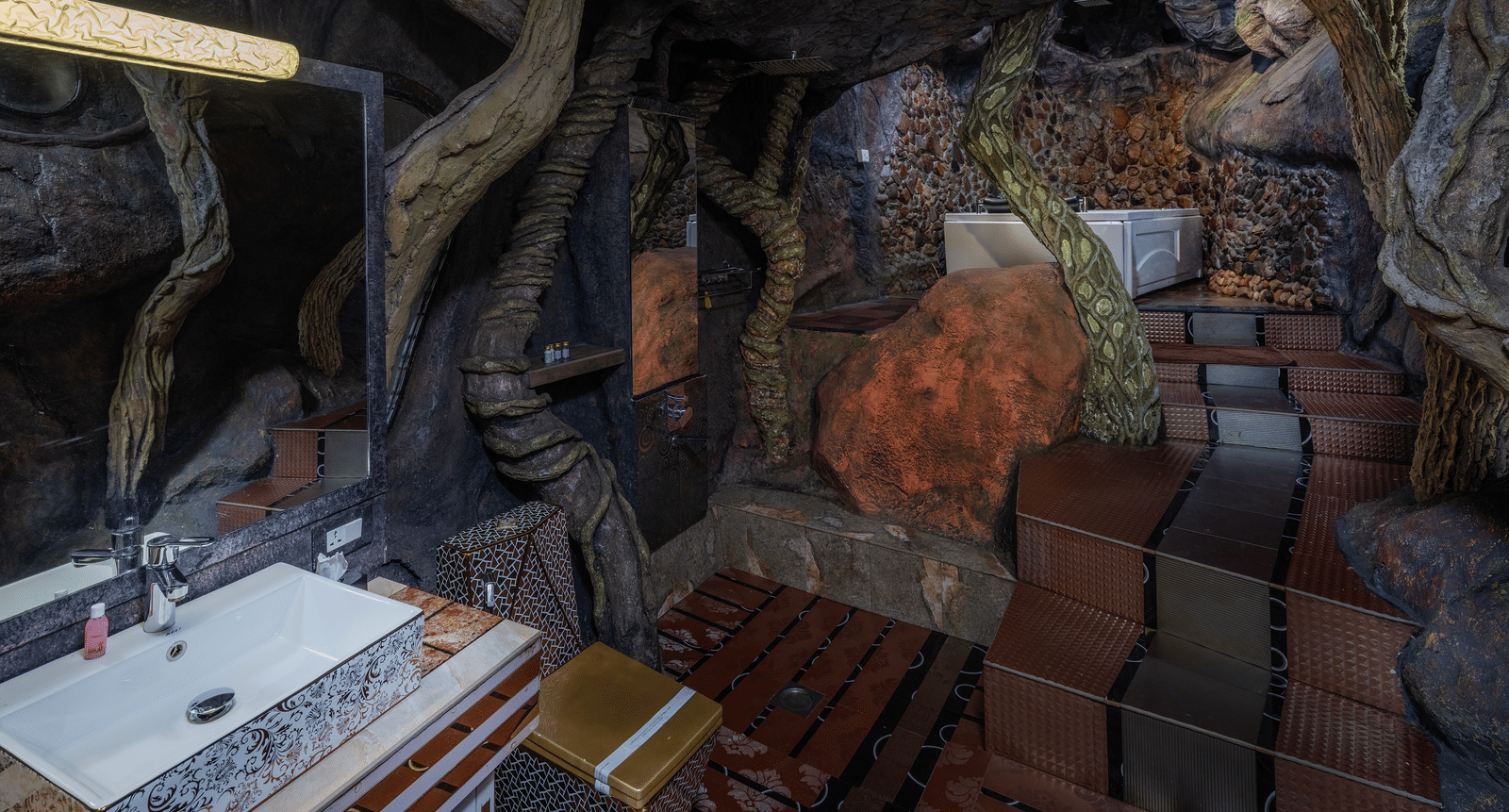 The interior of the Cave Room at Parakkat Nature Hotel and Resorts, Munnar, featuring a custom-designed floor, roots and vines forming part of the decor, and a vanity.