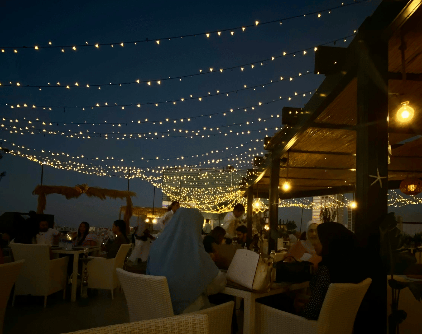 A dimly-lit open-sir dining area decorated with fairy lights.