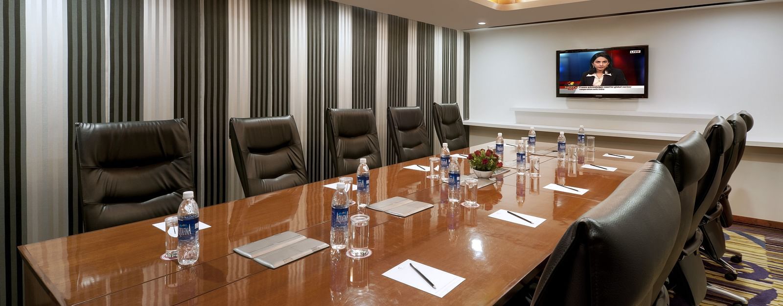 Modern boardroom with sleek wooden table and leather chairs, ideal for meetings at The Elanza Hotel.