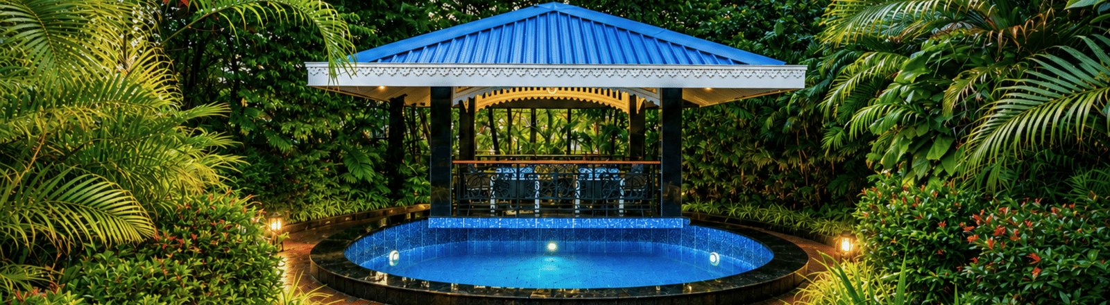 Garden gazebo with a blue pitched roof and a round plunge pool lit at dusk, framed by tropical planting at MAYFAIR Oasis Resort & Convention, Jharsuguda.