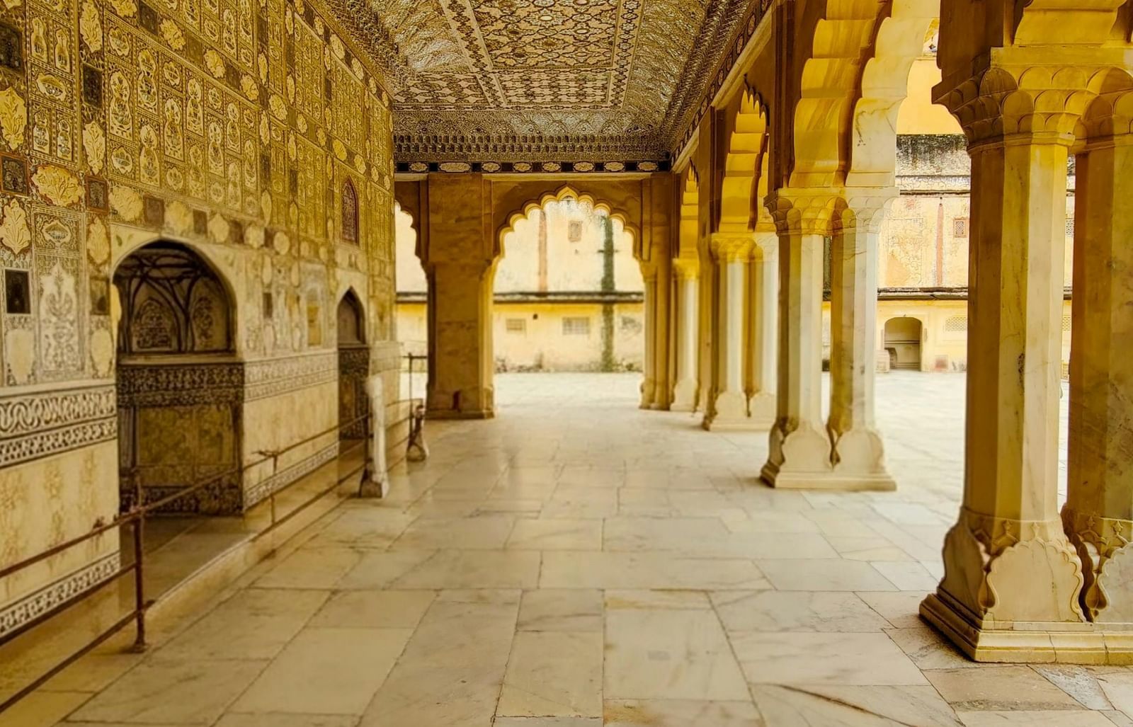 An ornate hallway with arched pillars and decorative ceilings, an architectural feature of Royal Heritage Haveli.