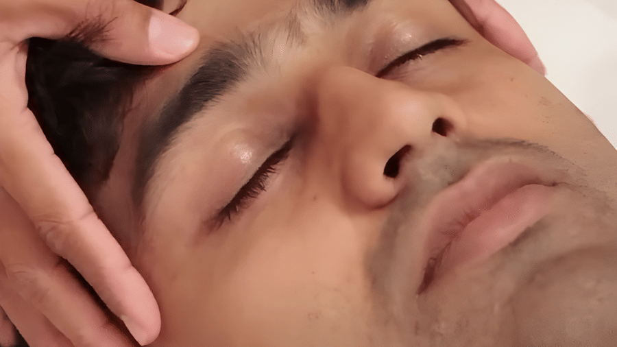 A close-up view of a hand massaging a man's forehead at Bamboo Saa Sunrise Wedding & Wellness Resort, Jaipur.