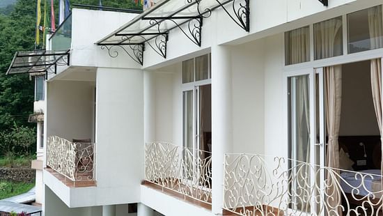 White villas with balconies, a swimming pool, and a foggy mountain view. - VITS Kunjham Retreat, Gangtok