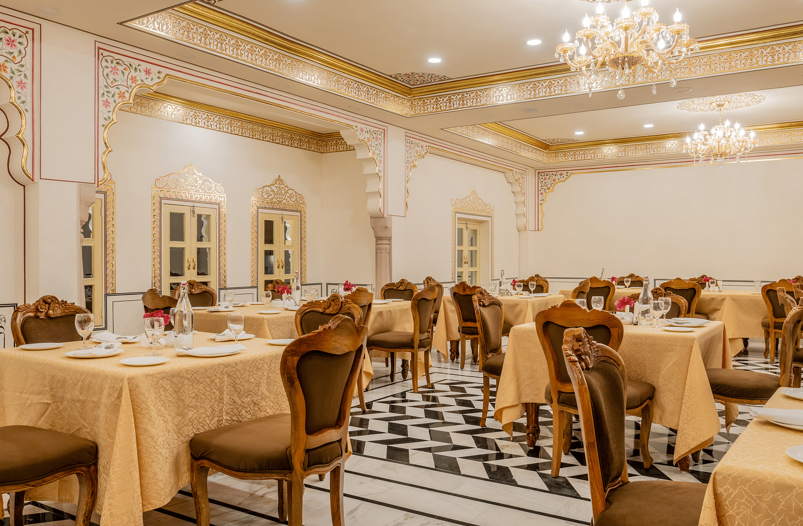 a brightly lit dining area with ample space to walk besides the beige table cloth cover dining tables - Brij Castle, Jaipur
