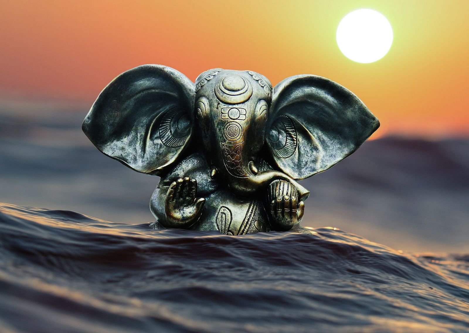 An AI image of the hindu deity Lord Ganesh's idol almost submerged in water with sun setting  in the background.