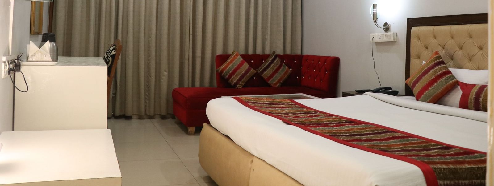 Guest room with bed, window drapes and seating area at Hotel Diamond Plaza, Chandigarh