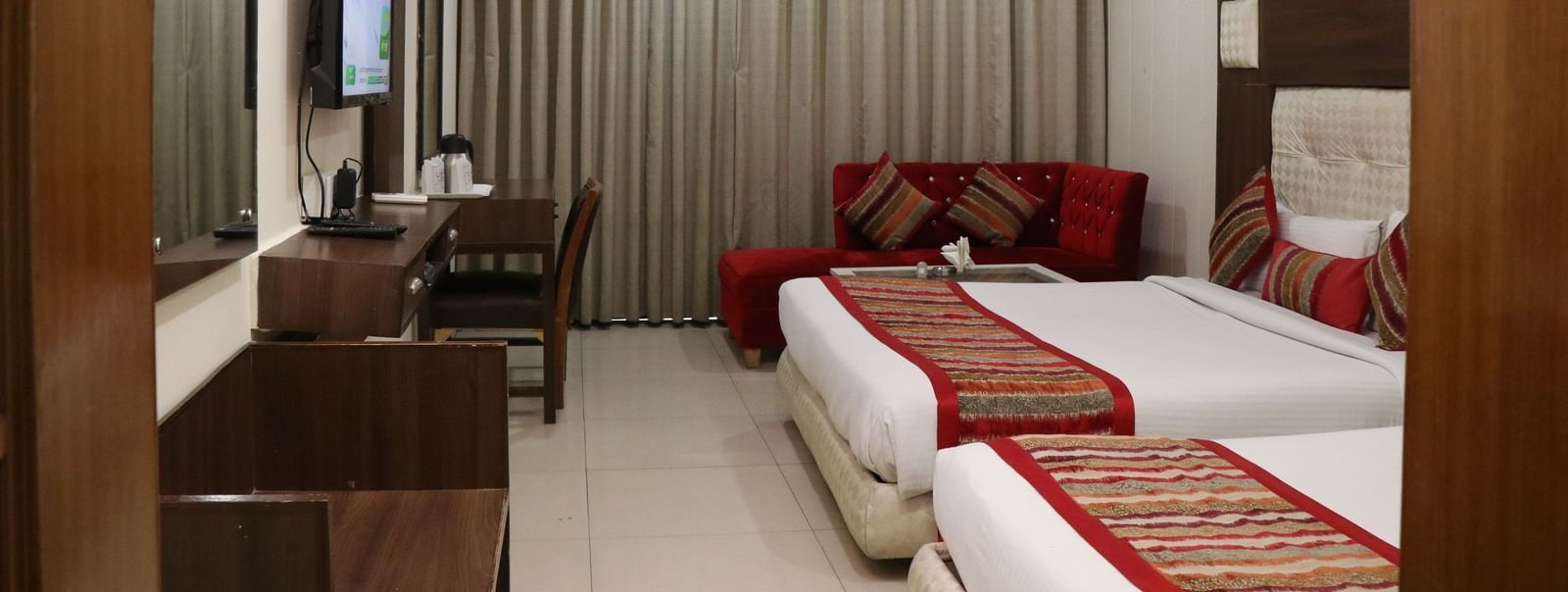 Modern hotel room with two queen size beds, a wall-mounted TV, and a cosy ambience - Hotel Diamond Plaza, Chandigarh.