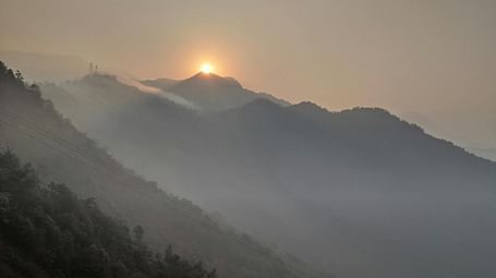 A hazy, muted landscape with mountains and a pale sun at the top.