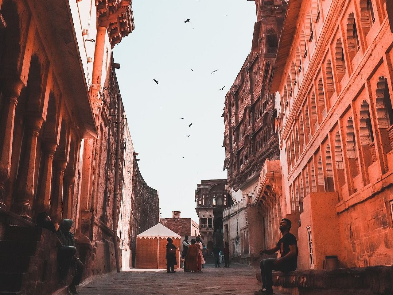 A pathway with historical buildings and people in the background.