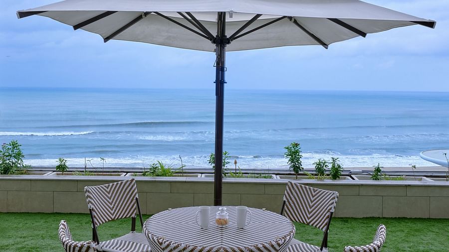 Sitting space with four chairs placed around a table of the Premium Room at Swosti Premium Beach Resorts in Puri with the view of the sea under a partially cloudy sky