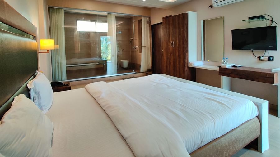 A Super Premium Room at The Kanila Resort with a queen sized bed, a nightstand, a TV, and a desk. 