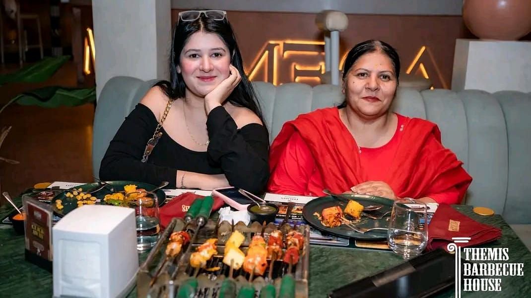 Guests posing for a photo with a spread of barbecue food in front at Themis Barbecue House, Ambala
