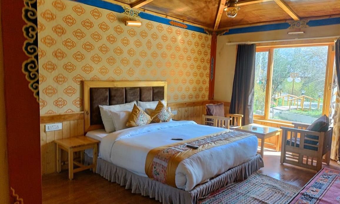 Premium Cottage at White Sands Resort, Ladakh with a king size bed, wooden walls, and a window view.