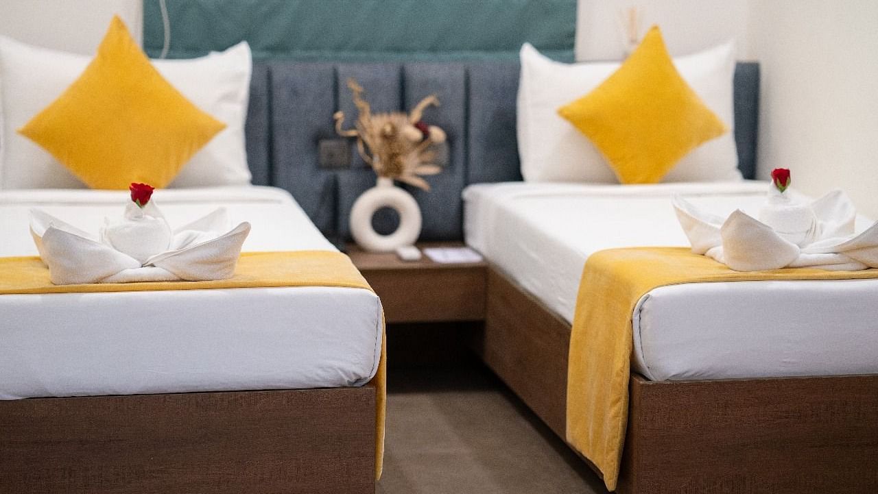 A twin room with two neatly made beds, accented with pillows and a decorative centrepiece on the bedside table at Hotel Kyzen Smartstays – Smart, Reliable, Kyzen